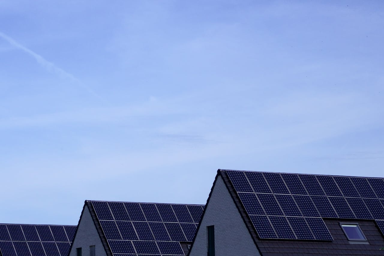 Home Modern Belgian houses with solar panels on rooftops under a clear blue sky.