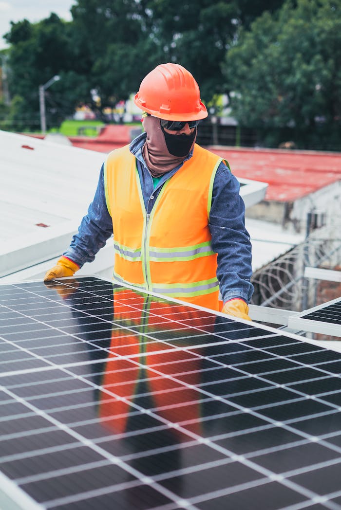 About Technician in protective gear installing solar panels on a sunny day.